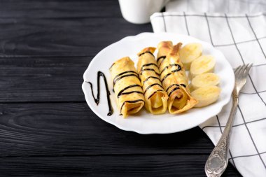 Süzme peynir ve çikolata şurubu ile bir muz krep.