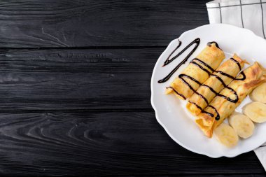 Süzme peynir ve çikolata şurubu ile bir muz krep.