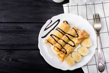 Süzme peynir ve çikolata şurubu ile bir muz krep.