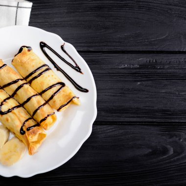 Krep muz ile siyah ahşap zemin üzerine çikolata şurubu ile dekore edilmiştir. Kopya alanı ile Üstten Görünüm.