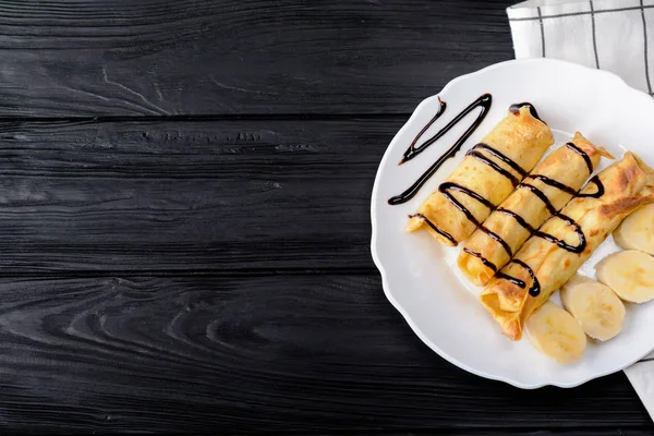 Süzme peynir ve çikolata şurubu ile bir muz krep.