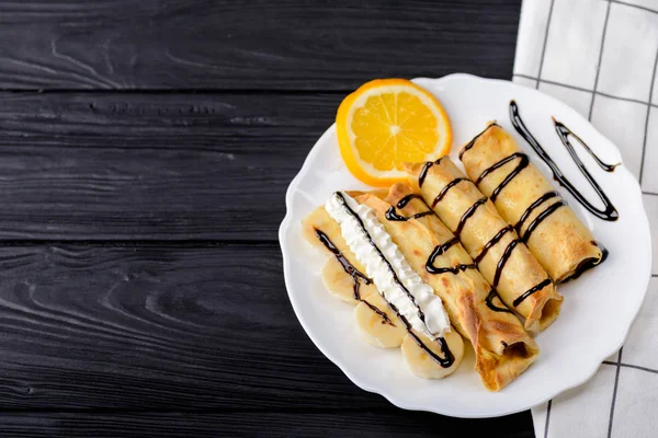 Krep muz, siyah ahşap zemin üzerine çikolata şurubu ile süslenmiş krem şanti. Kopya alanı ile Üstten Görünüm.