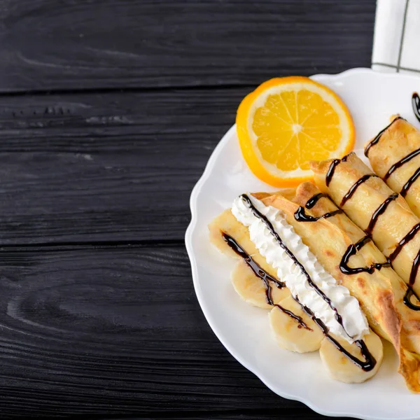 Krep muz, siyah ahşap zemin üzerine çikolata şurubu ile süslenmiş krem şanti. Kopya alanı ile Üstten Görünüm.