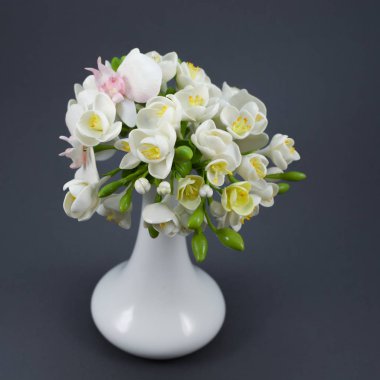 Polymer clay flower bouquet in a white vase on a gray background clipart