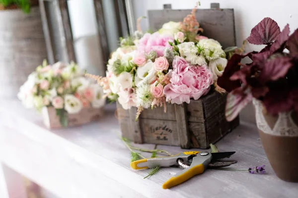 Bridal bouquets of flowers for wedding event. White and pink roses bridal bouquets of flowers in a wooden vintage boxes inside florist shop.