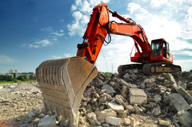 Paletli ekskavatör yıkım sitede. Yıkım sitesinde çalışan bir büyük Paletli ekskavatör önden görünümü.