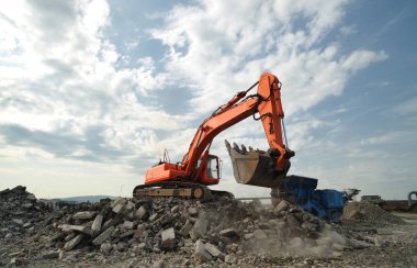 Yıkım inşaat alanında çalışma etkinliği. Paletli ekskavatör ve taş ayırıcı makinelerin Montaj cihazları-Kırıcı sitesinde çalışan.