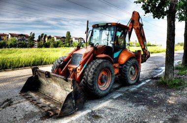 Ekskavatör sokakta park edilmiş. Büyük Ekskavatör ağaç gölge karayolu üzerinde park.