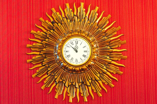 Vintage golden clock. Big vintage clock on the wall with red  wallpaper.