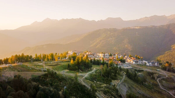 Rosa Khutor plateau, buildings, slopes and chair lifts. Aerial view at sunset 