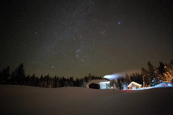 Pequena casa no fundo do céu estrelado de inverno — Fotografia de Stock