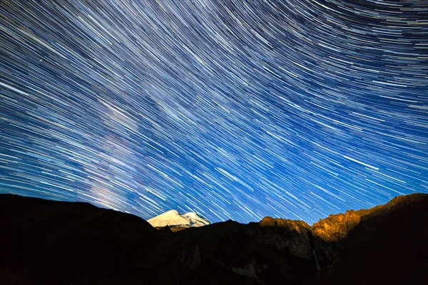 Stjärnor Rita blekning linjer och moln över Mount Elbrus. Natt mark — Stockfoto