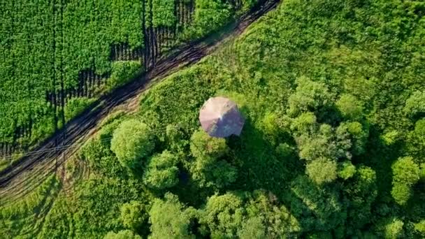 Montez au-dessus du château d'eau avec rotation. La tête sur la balle. Vue sur le chemin de terre, prairie, buissons et champ de pommes de terre. Vidéo. UltraHD (4K )