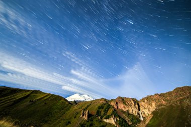Yıldız solma çizgiler ve bulutlar üzerinde Elbruz Dağı çizme. Gece arazi