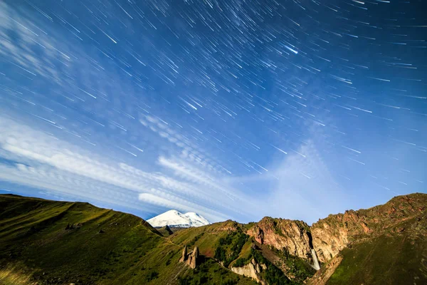 Stjärnor Rita blekning linjer och moln över Mount Elbrus. Natt mark — Stockfoto