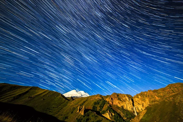 Αστέρια σχεδιάσετε γραμμές ξεθώριασμα και σύννεφα πάνω από το όρος Ελμπρούς. Νύχτα γης — Φωτογραφία Αρχείου