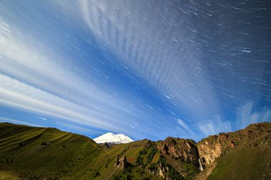 Yıldız solma çizgiler ve bulutlar üzerinde Elbruz Dağı çizme. Gece arazi