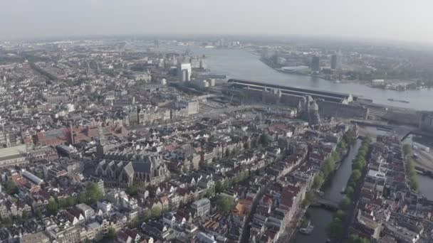 Amsterdam, Pays-Bas. Survoler les toits de la ville en direction de la gare centrale d'Amsterdam (Amsterdam Centraal) et autour de l'église Oudekerk (De Oude Kerk). 4K — Video