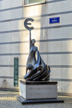 Brüksel, Belçika - 3 Temmuz 2019: Avrupa, Avrupa Parlamentosu binasının yanında avro sembolü tutan bir kadının bronz heykeli. Avronun sembolü olan 