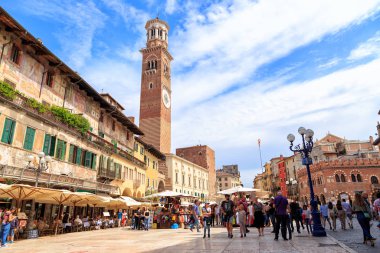 Verona, Italy - July 15, 2019: Stalls and malls at Piazza Erbe, Lamberti Tower - 