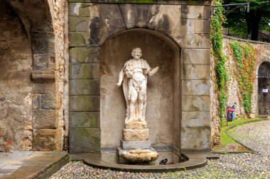 Bergamo, İtalya. Tabanda deniz kabuğu olan bir adamın antik heykeli. Şehrin tarihsel kısmı. Yukarı şehir. Yağmurlu hava