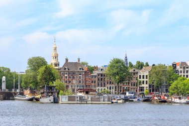 Amsterdam, Hollanda - 30 Haziran 2019: Prins Hendrikkade sokağı konut binalarıyla doludur. Sabah Amsterdam tarihi şehir merkezi