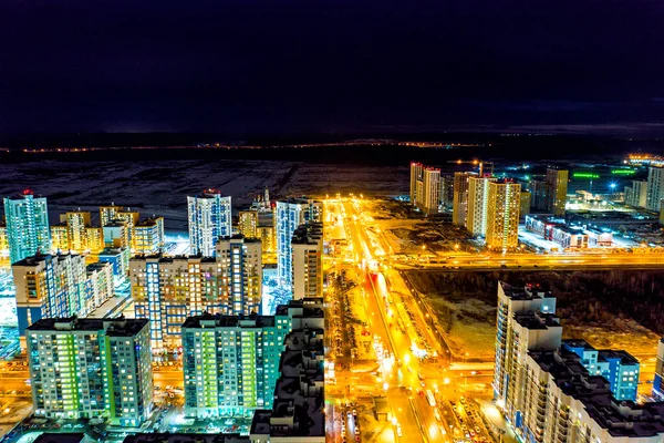 Yekaterinburg, Russia. A wide highway lit by lanterns with pedestrian walkways. Residential area with new buildings. Night city view