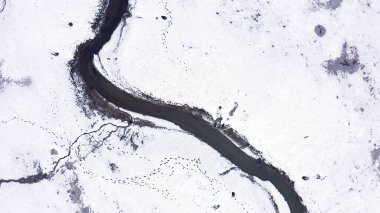 Karla kaplı küçük bir nehri olan bataklıklar. Vahşi hayvanların pek çok ayak izi, Havadan Bakış, Kafadan Vurma  