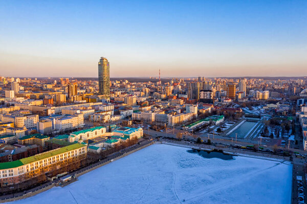 Yekaterinburg, Russia - March 23, 2020: Aerial view of the city during sunset. Embankment of the central pond and dam. Early spring