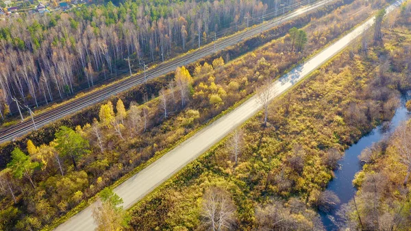Russia, Ural, Ekaterinburg. Dark river on a background of autumn forest. Electrified Railway. Highway. Sunset light, Aerial View