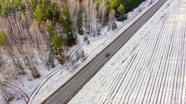 道路上の青い車に乗る 畑や森の周りは雪に覆われています ロシア ウラル 空中ビュー — ストック写真