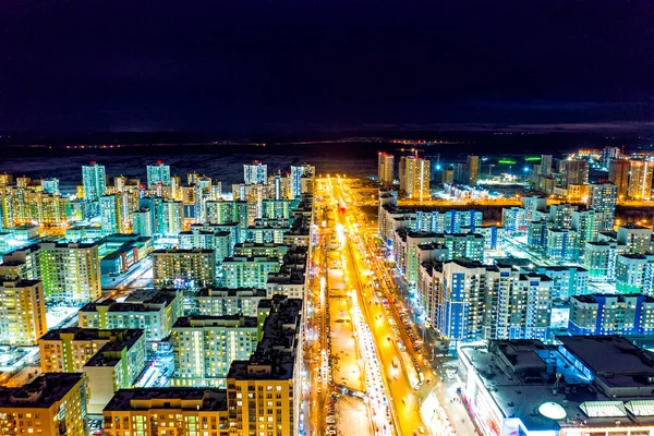 Yekaterinburg, Russia. A wide highway lit by lanterns with pedestrian walkways. Residential area with new buildings. Night city view