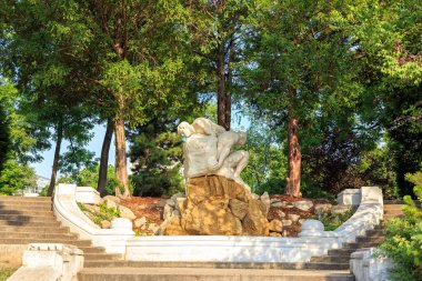 Viyana, Avusturya - 20 Temmuz 2019: İki adam bir taşı yuvarlıyor. Gezinti güvertesindeki merdivenlerde heykel. Viyana Şehir Parkı