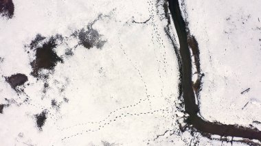 Karla kaplı küçük bir nehri olan bataklıklar. Vahşi hayvanların pek çok ayak izi, Havadan Bakış, Kafadan Vurma  