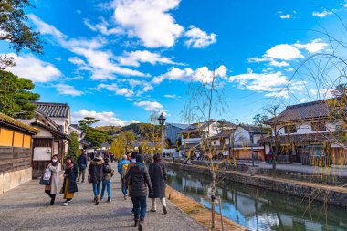 Okayama, Japonya - 30 Aralık 2018: Kurashiki Bikan Tarihi Bölgesi. Kurashiki Nehri 'nin kıyılarında söğüt ağaçları ve konutlardan oluşan Japon beyaz duvarlarıyla bilinen şehir manzarası