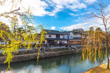 Okayama, Japonya - 30 Aralık 2018: Kurashiki Bikan Tarihi Bölgesi. Kurashiki Nehri 'nin kıyılarında söğüt ağaçları ve konutlardan oluşan Japon beyaz duvarlarıyla bilinen şehir manzarası
