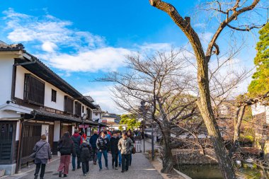 Okayama, Japonya - 30 Aralık 2018: Kurashiki Bikan Tarihi Bölgesi. Kurashiki Nehri 'nin kıyılarında söğüt ağaçları ve konutlardan oluşan Japon beyaz duvarlarıyla bilinen şehir manzarası