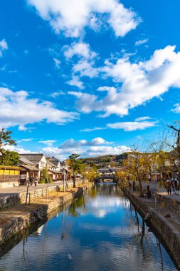 Okayama, Japonya - 30 Aralık 2018: Kurashiki Bikan Tarihi Bölgesi. Kurashiki Nehri 'nin kıyılarında söğüt ağaçları ve konutlardan oluşan Japon beyaz duvarlarıyla bilinen şehir manzarası