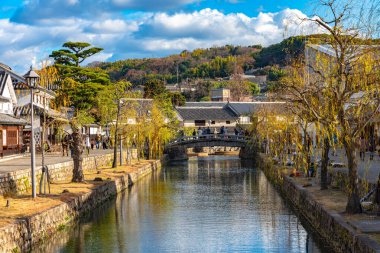 Okayama, Japonya - 30 Aralık 2018: Kurashiki Bikan Tarihi Bölgesi. Kurashiki Nehri 'nin kıyılarında söğüt ağaçları ve konutlardan oluşan Japon beyaz duvarlarıyla bilinen şehir manzarası