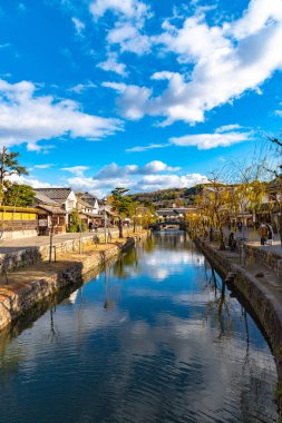 Okayama, Japonya - 30 Aralık 2018: Kurashiki Bikan Tarihi Bölgesi. Kurashiki Nehri 'nin kıyılarında söğüt ağaçları ve konutlardan oluşan Japon beyaz duvarlarıyla bilinen şehir manzarası