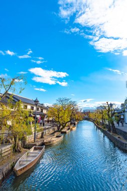 Okayama, Japonya - 30 Aralık 2018: Kurashiki Bikan Tarihi Bölgesi. Kurashiki Nehri 'nin kıyılarında söğüt ağaçları ve konutlardan oluşan Japon beyaz duvarlarıyla bilinen şehir manzarası