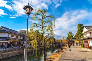 Okayama, Japonya - 30 Aralık 2018: Kurashiki Bikan Tarihi Bölgesi. Kurashiki Nehri 'nin kıyılarında söğüt ağaçları ve konutlardan oluşan Japon beyaz duvarlarıyla bilinen şehir manzarası