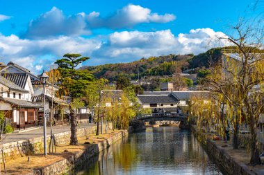 Okayama, Japonya - 30 Aralık 2018: Kurashiki Bikan Tarihi Bölgesi. Kurashiki Nehri 'nin kıyılarında söğüt ağaçları ve konutlardan oluşan Japon beyaz duvarlarıyla bilinen şehir manzarası