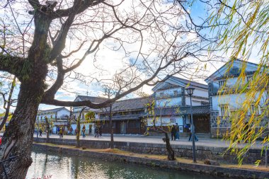 Okayama, Japonya - 30 Aralık 2018: Kurashiki Bikan Tarihi Bölgesi. Kurashiki Nehri 'nin kıyılarında söğüt ağaçları ve konutlardan oluşan Japon beyaz duvarlarıyla bilinen şehir manzarası