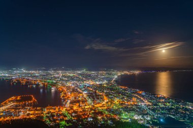 Hakodate City gece görüşü. Hakodate gözlemevi, denizde parlak bir ay ışığı, yüzeyde altın yansıması. Dünyanın en ünlü manzaralı yeri. Hokkaido, Japonya