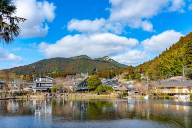 Kışın güneşli bir günde açık mavi gökyüzü ile Altın Pul Gölü ve Yufu Dağı. Bu popüler gezi yeri turistler tarafından sıklıkla izleniyor ve fotoğraflanıyor. Yufuin, Oita Bölgesi, Japonya