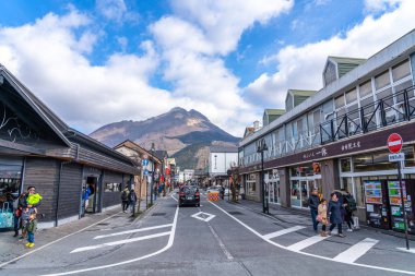 Yufuin, Oita Bölgesi, Japonya - 5 Ocak 2020: Açık mavi gökyüzü ile kış güneşli bir günde Yufuin şehri. Sokakta bir sürü dükkan var, turistler yeni yıl tatili için buraya geliyor.