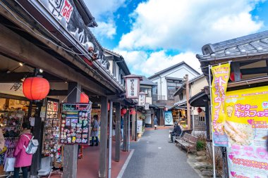 Yufuin, Oita Bölgesi, Japonya - 5 Ocak 2020: Açık mavi gökyüzü ile kış güneşli bir günde Yufuin şehri. Sokakta bir sürü dükkan var, turistler yeni yıl tatili için buraya geliyor.