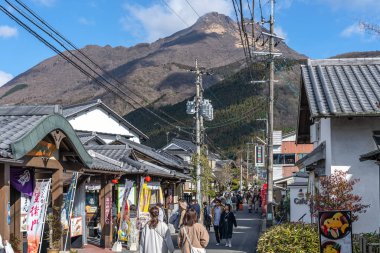 Yufuin, Oita Bölgesi, Japonya - 5 Ocak 2020: Açık mavi gökyüzü ile kış güneşli bir günde Yufuin şehri. Sokakta bir sürü dükkan var, turistler yeni yıl tatili için buraya geliyor.