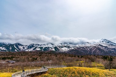 Hokkaido, Japan - May 06 2019 : Shiretoko Goko Five Lakes in Shiretoko National Park. Rolling mountain range and wetland in springtime. Tourists can walk on the elevated wooden boardwalk